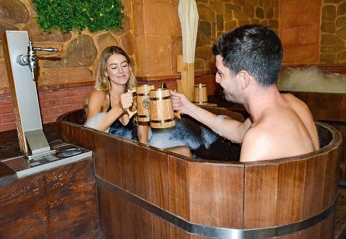 A entrada do Gran Hotel Almeria é mostrada, com portas de vidro, paredes de azulejos cinza e plantas em vasos ao lado.