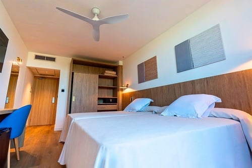 una habitación con dos camas y un ventilador de techo