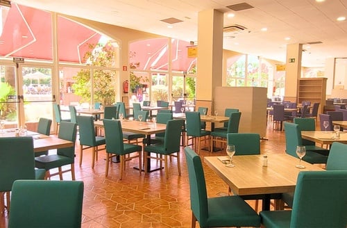 Comedor del Hotel todo incluido en La Pineda | Ohtels La Hacienda, con mesas y sillas verdes.