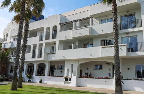 Hotel em Cabo de Gata: fachada branca com palmeiras, varandas e jardim. Reserve já!
