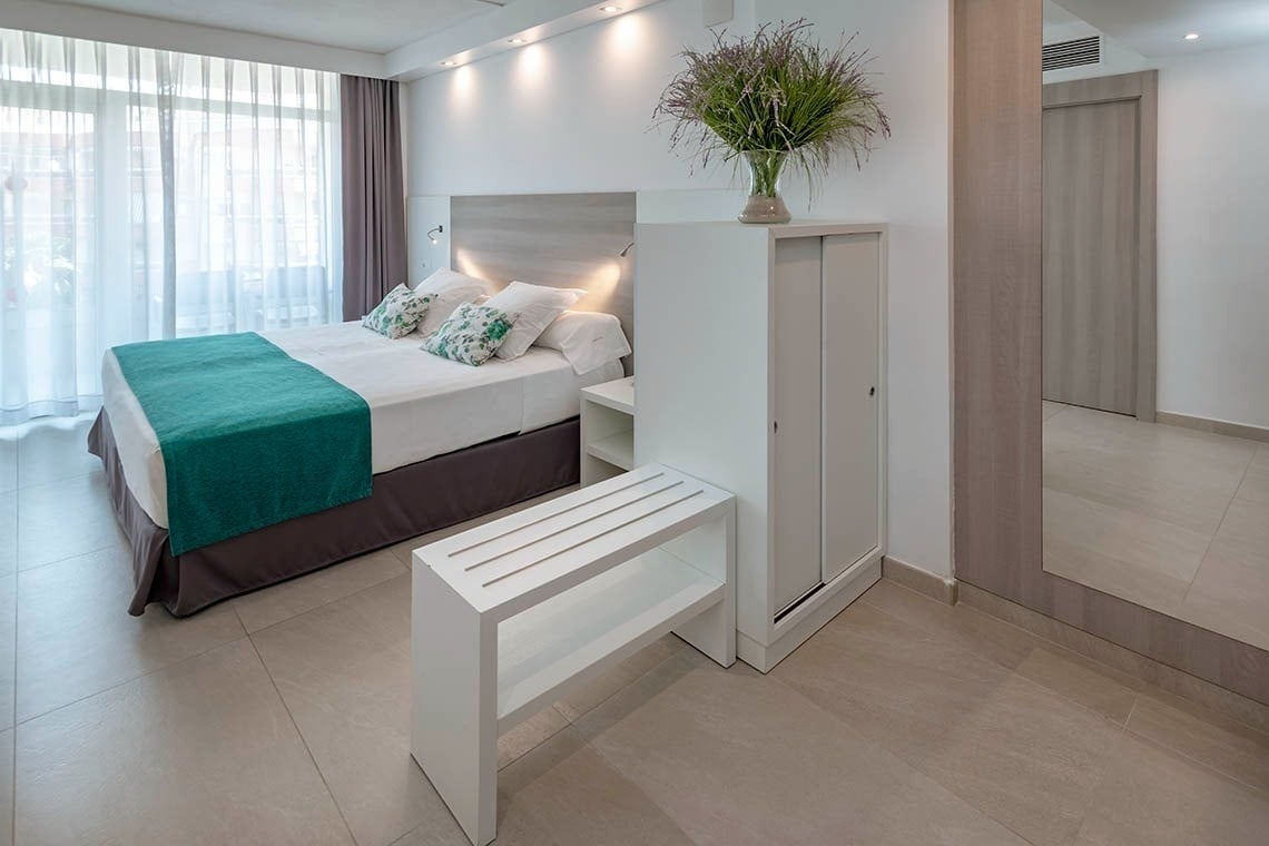 una habitación de hotel con una cama y un banco