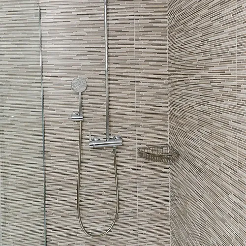 Moderne Dusche im Olympus Palace mit Fliesen und Seifenhalter.