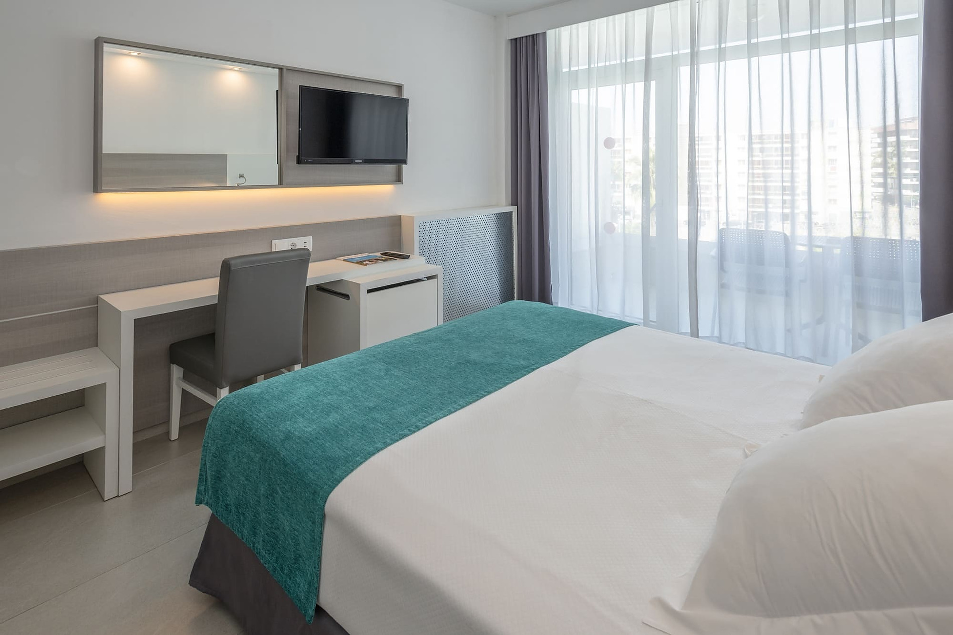 Olympus Palace Zimmer: Bett, Schreibtisch und Fenster mit Vorhängen.