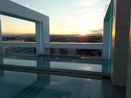 a swimming pool with a view of a city at sunset