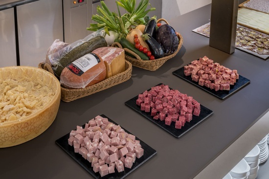 a variety of meats and vegetables on a table including a sliced ham