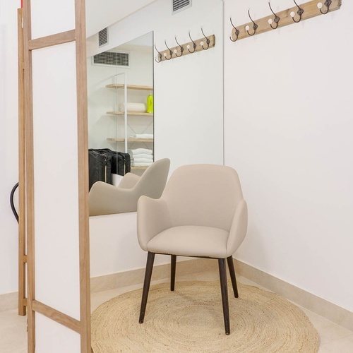 una habitación blanca con una silla y un espejo