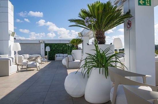 una terraza con muebles blancos y plantas en macetas