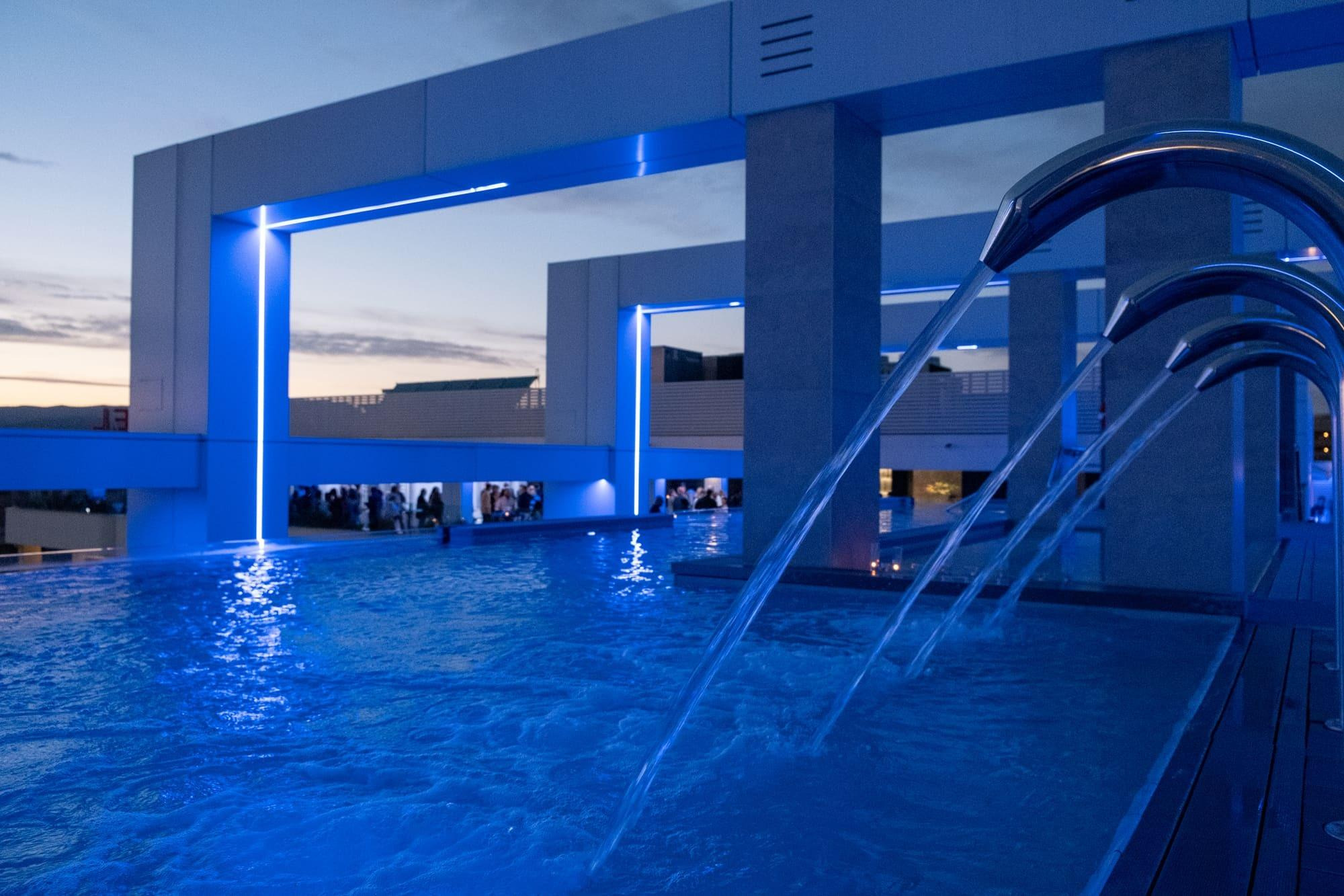 Illuminated pool with waterfalls at Olympus Palace, blue night.