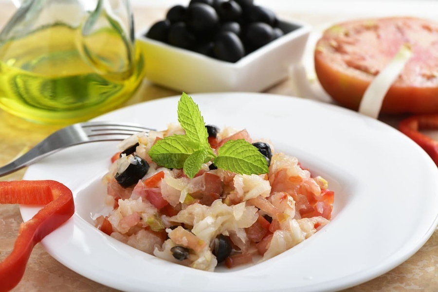 un plato de ensalada con tomates y aceitunas negras