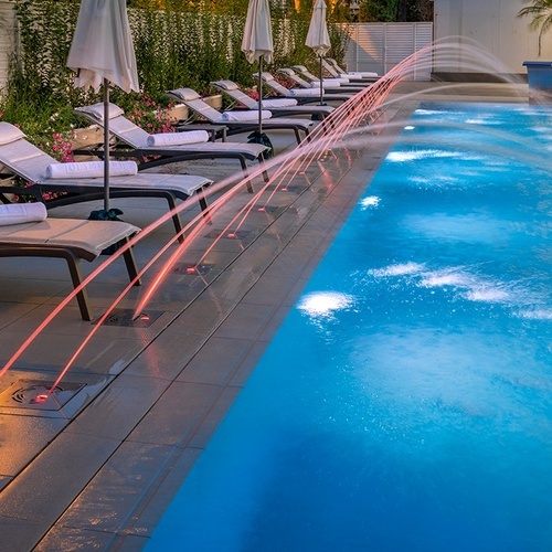 una piscina rodeada de sillas y sombrillas y una fuente