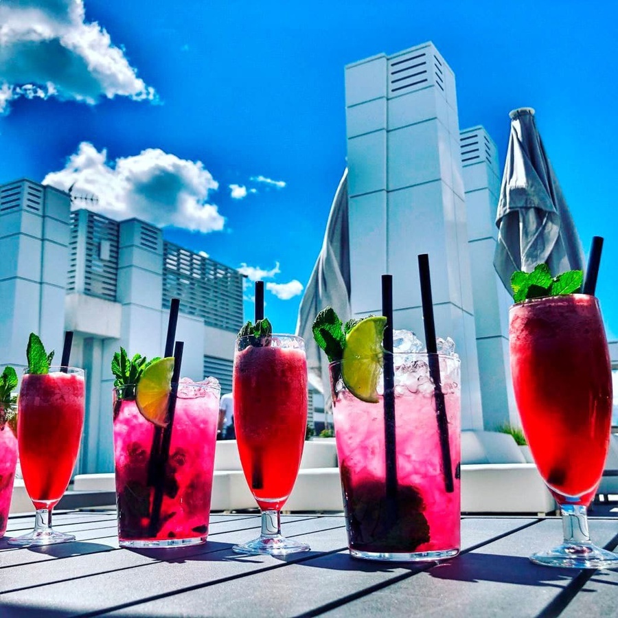 una fila de bebidas rosas con pajitas en una mesa
