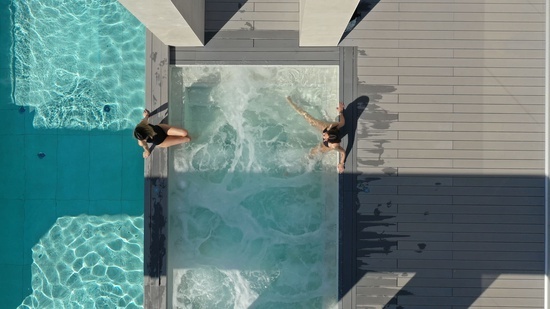 an aerial view of two people swimming in a pool