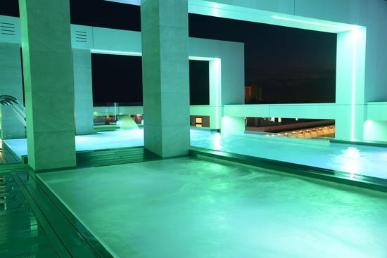 a swimming pool is lit up with green lights at night