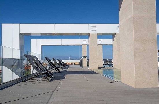 a deck with chairs and a swimming pool in the background