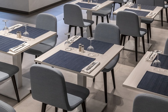 a restaurant filled with tables and chairs with blue place mats