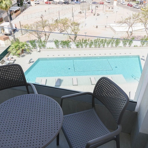 una vista de una piscina desde un balcón con una mesa y sillas