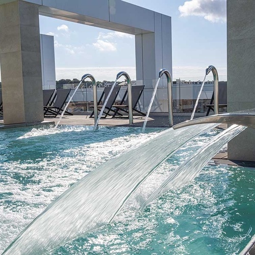 una piscina con fuentes y sillas en el fondo