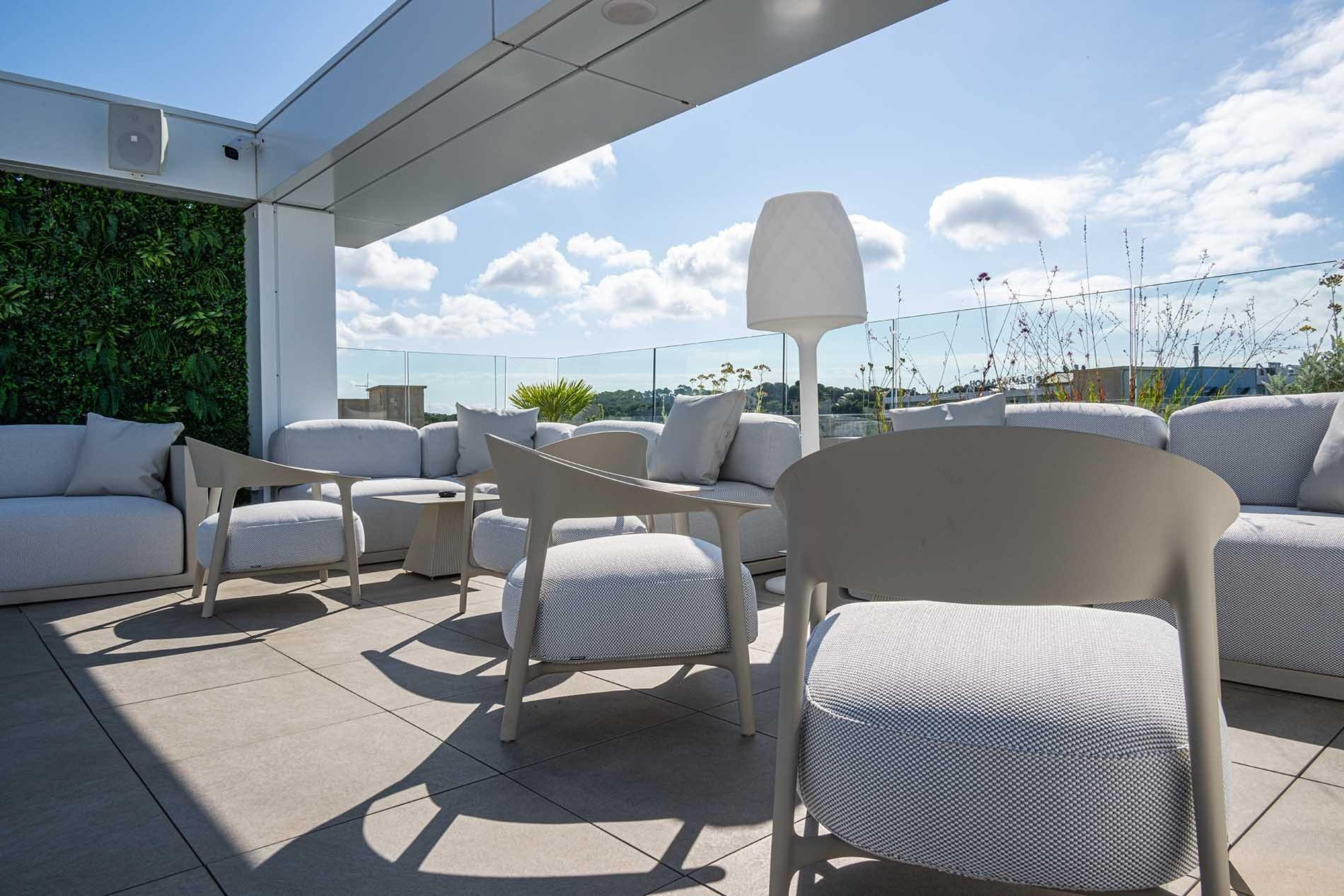 Terrasse Olympus Palace : mobilier design avec vue sur mer et végétation.