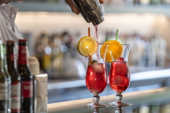 a bartender pours a drink into a glass with a straw
