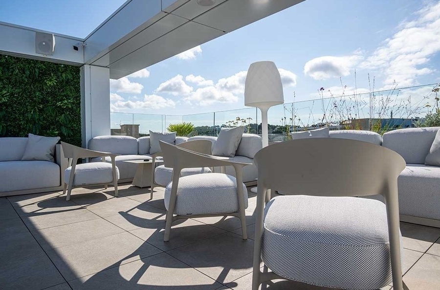 a patio with a couch and chairs and a lamp