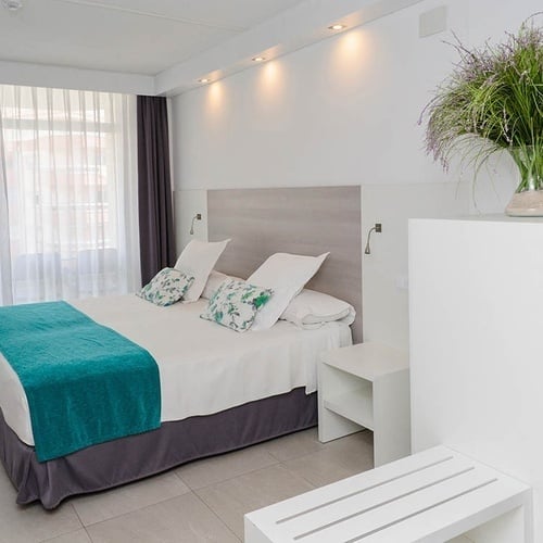 una habitación de hotel con una cama y un jarrón de flores