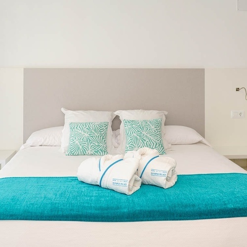 una cama en una habitación con una manta azul y toallas blancas