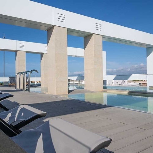 una fila de sillas junto a una piscina con columnas blancas