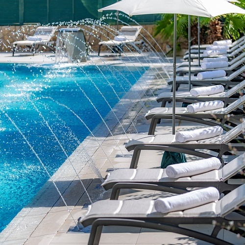 una fila de sillas y sombrillas junto a una piscina
