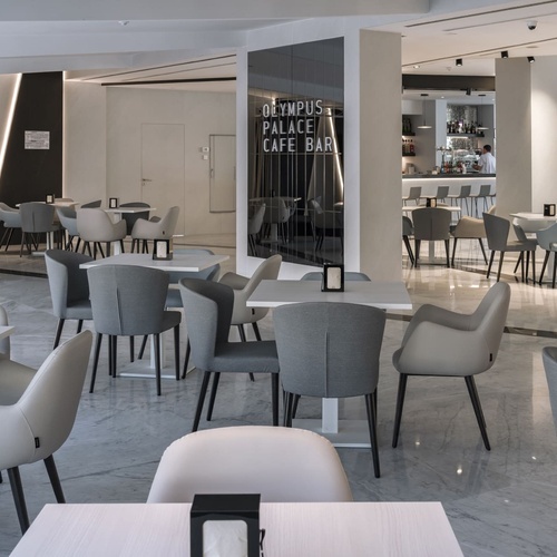 un restaurante lleno de mesas y sillas con la palabra olympus en la pared