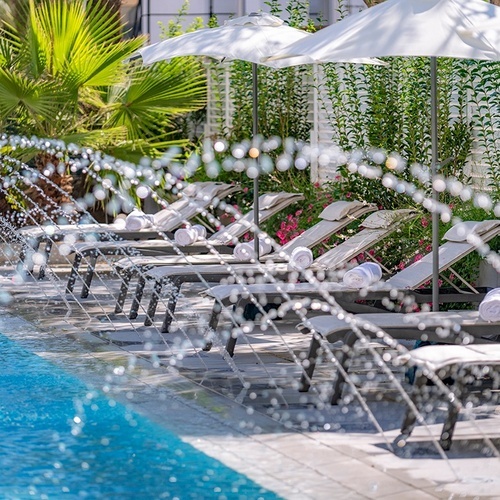 una piscina rodeada de sillas y sombrillas y una fuente