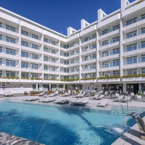 un gran edificio blanco con una piscina al frente