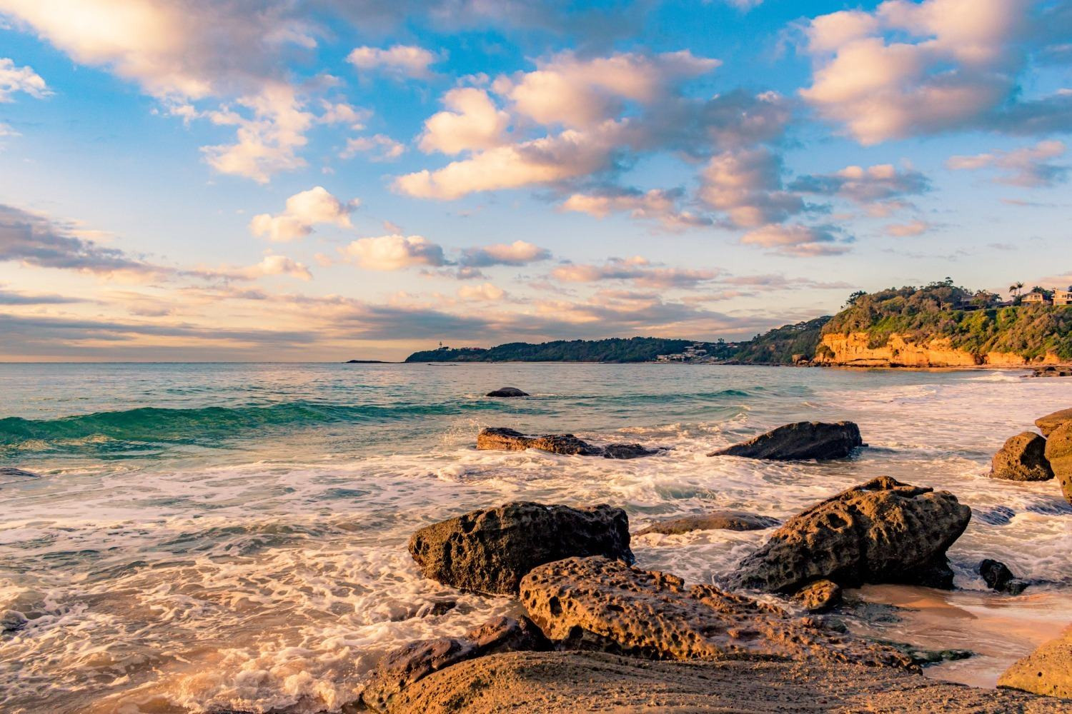 Goldener Strand bei Sonnenuntergang nahe Olympus Palace, Meer und Felsen.