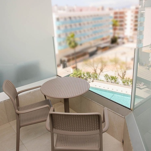 una mesa y dos sillas en un balcón con vistas a una piscina