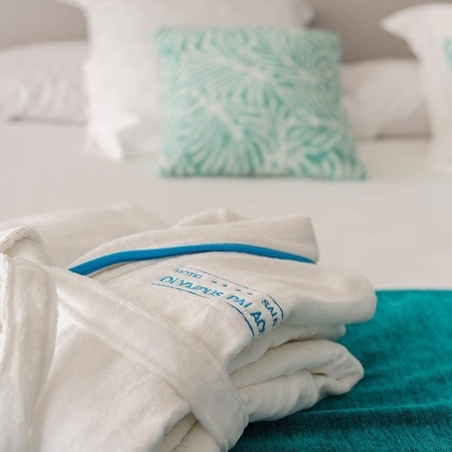 una bata blanca con el logotipo del hotel olympus está sobre una cama