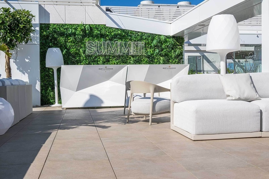 un patio con muebles blancos y una pared verde que dice summit