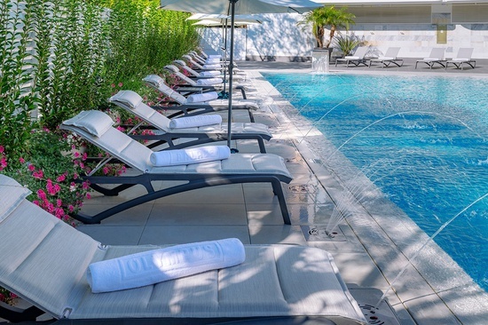 a row of lounge chairs next to a swimming pool