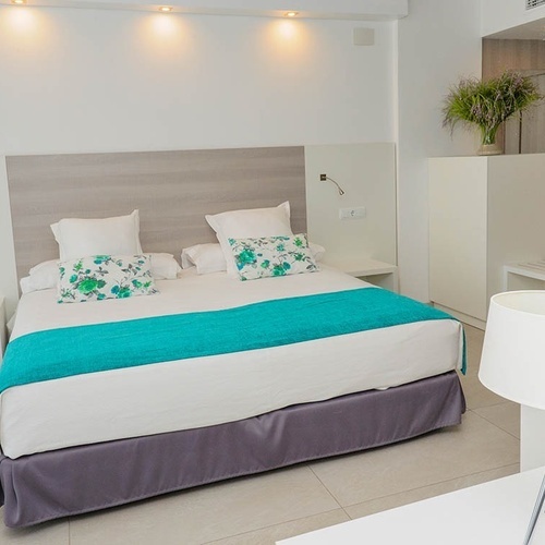 una habitación blanca con una cama y una lámpara