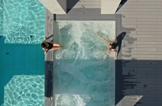 two women are sitting on the edge of a swimming pool