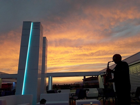 a man playing a saxophone in front of a sunset