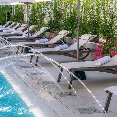 una piscina rodeada de sillas y sombrillas con toallas encima