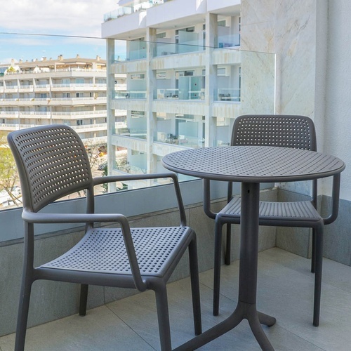 una mesa y dos sillas en un balcón con un edificio en el fondo