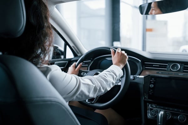 a woman in a white shirt is driving a car