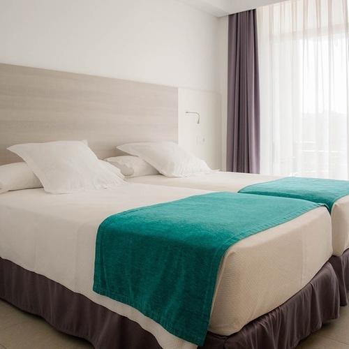 una habitación con dos camas y una cortina blanca