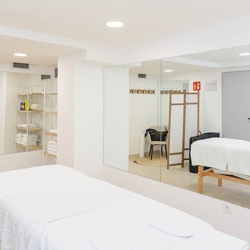 una habitación con dos camas de masaje y espejos