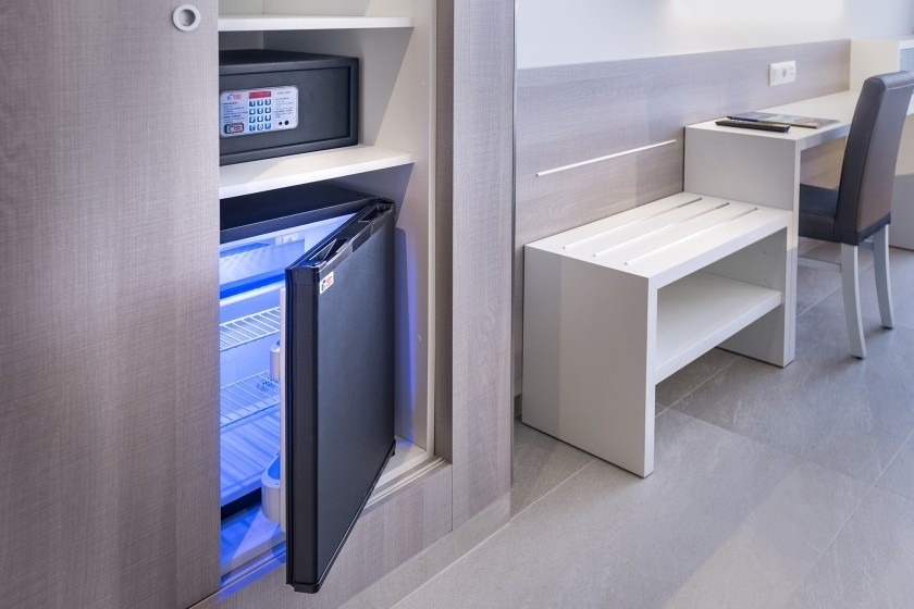 un pequeño refrigerador con la puerta abierta y una caja fuerte en el fondo