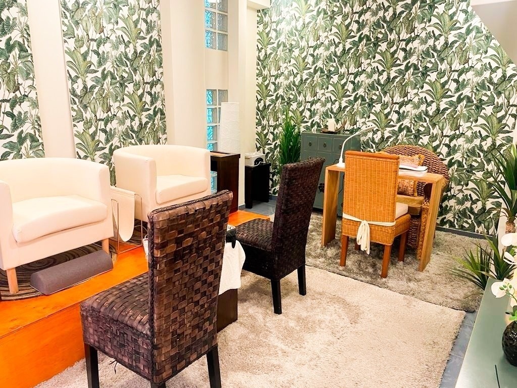 two chairs and a table in a room with tropical wallpaper