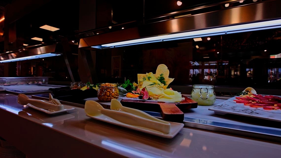 a buffet line with plates of food and jars of nuts