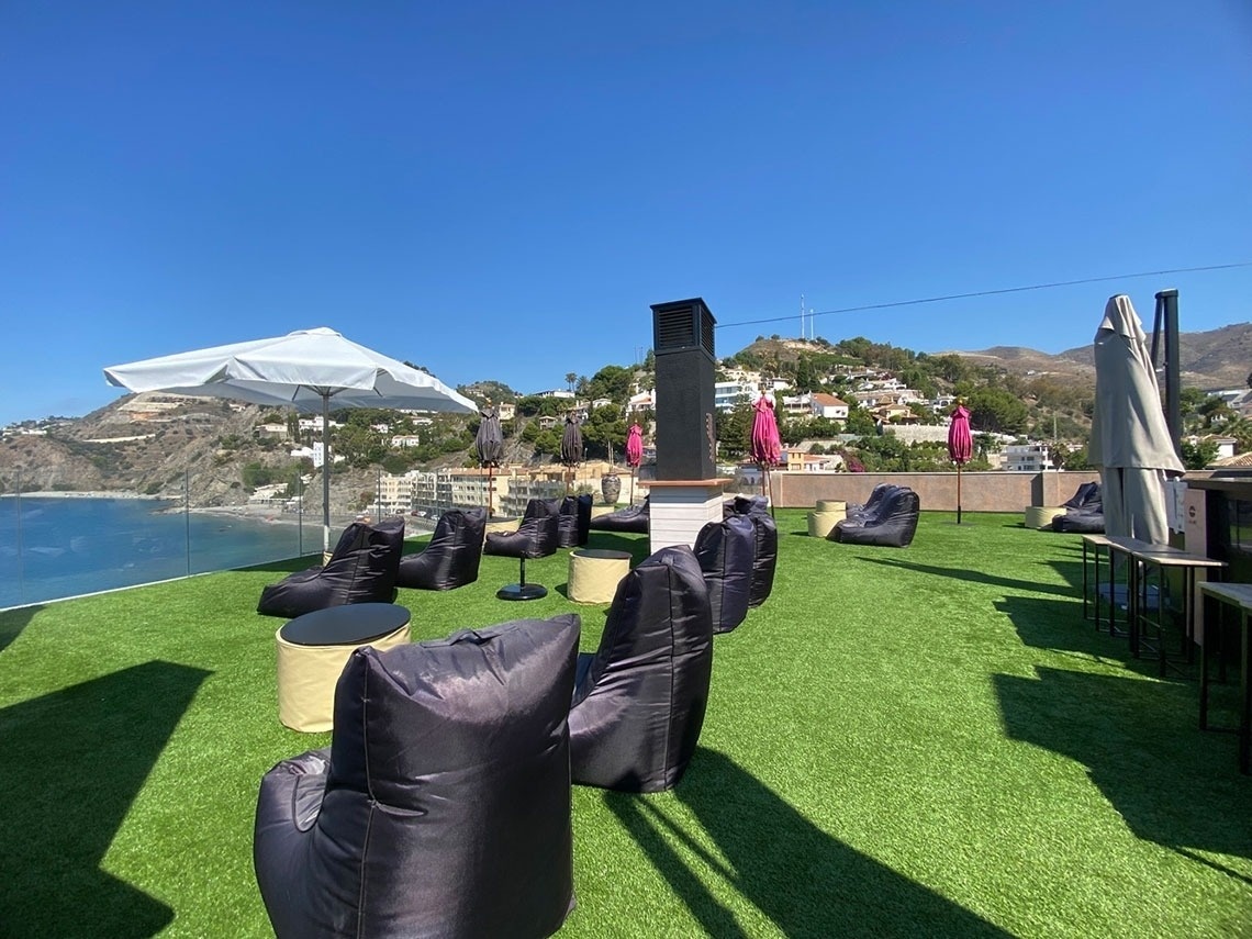 bean bag chairs and tables on a rooftop overlooking the ocean