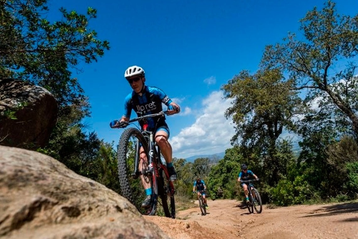 um homem está andando de bicicleta em uma estrada de terra