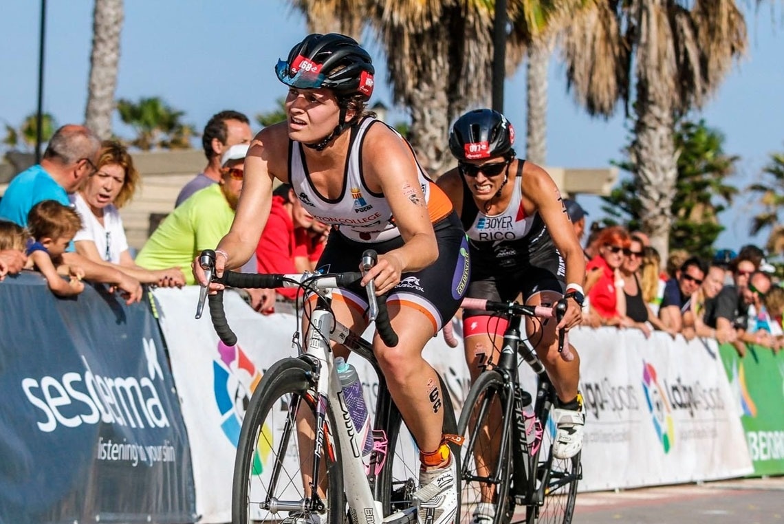 Eine Frau fährt mit einem Fahrrad in einem Rennen und trägt einen Helm mit der Aufschrift esther rico